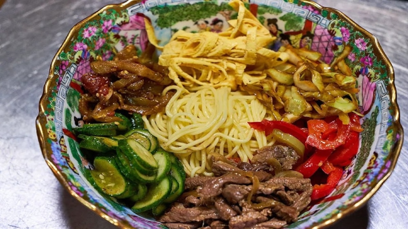 Куксу готовят из лапши, холодного бульона, мяса, овощей и яйца Куксу готовят из лапши, холодного бульона, мяса, овощей и яйца
